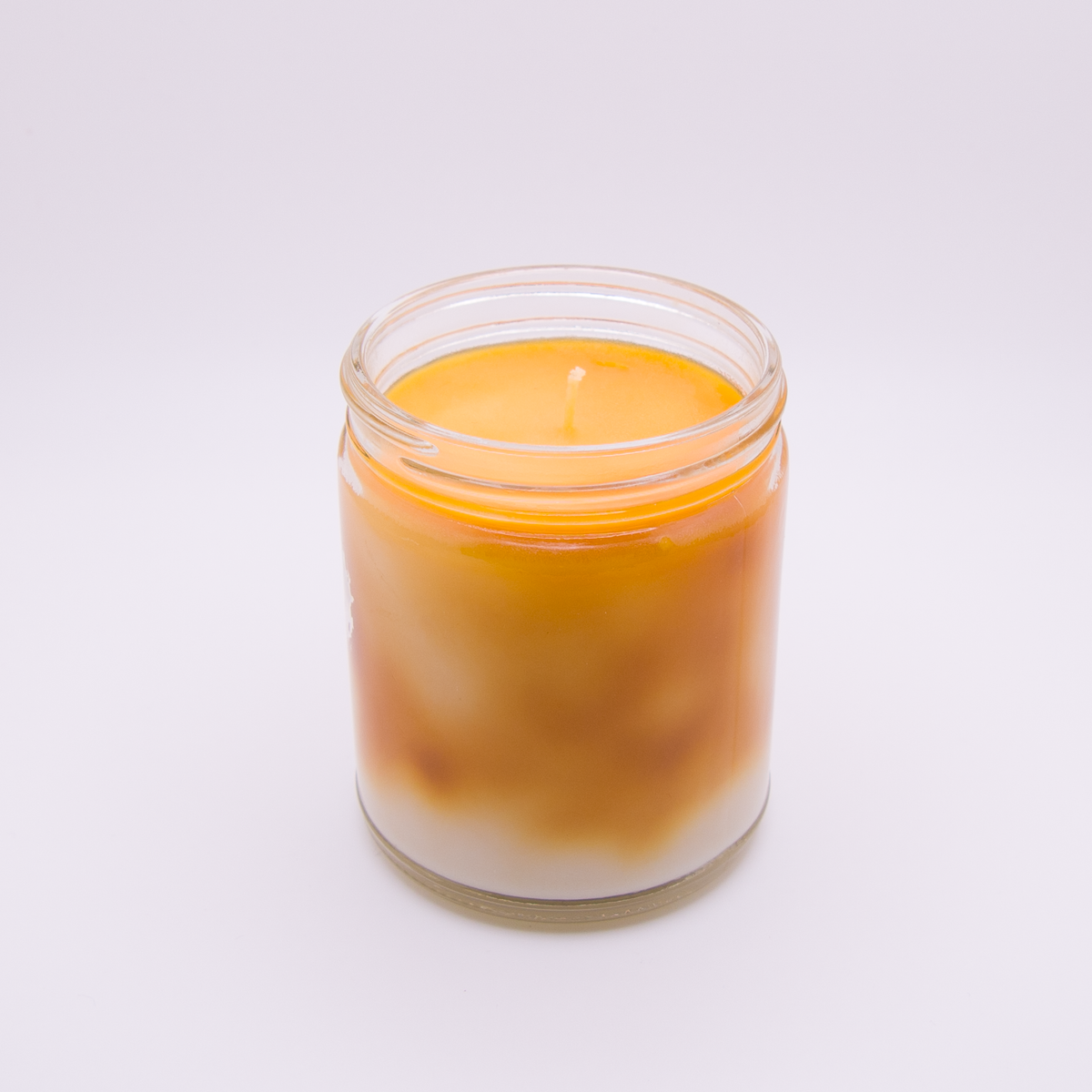 Butterscotch Bomb hand-poured parasoy candle in a clear glass jar with colored wax marbled into a tie-dye effect in orange and brown - Swearingen Candle Co.
