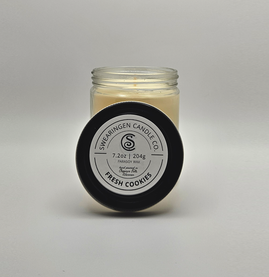 Fresh Cookies hand-poured parasoy candle in a clear glass jar with a black lid, shown in a three quarter view - Swearingen Candle Co.